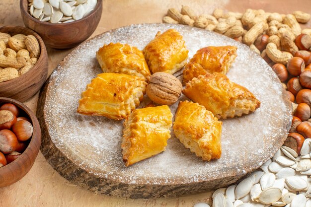 Vista frontal deliciosos pasteles de nueces con nueces en la mesa de luz pastel de tarta pastelería dulce