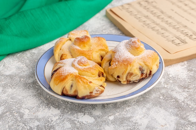 Vista frontal deliciosos pasteles con relleno dentro de la placa sobre la mesa blanca, pastel dulce hornear fruta de pastelería