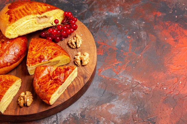 Vista frontal deliciosos pasteles en rodajas con frutos rojos sobre la mesa oscura pastel de pastel de pastelería dulce