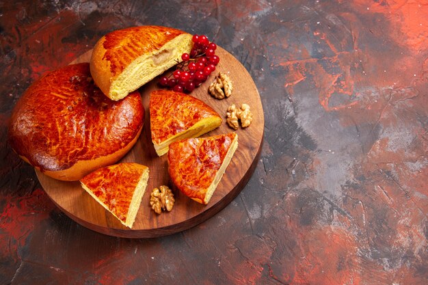 Vista frontal deliciosos pasteles en rodajas con frutos rojos sobre la mesa oscura pastel de pastel de pastelería dulce