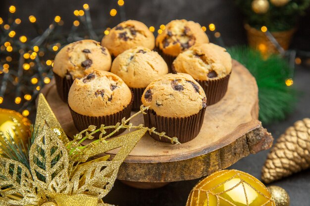 Vista frontal deliciosos pasteles con sabor a fruta alrededor de los juguetes del árbol de vacaciones sobre fondo oscuro, pastel de postre, dulces, crema fotográfica