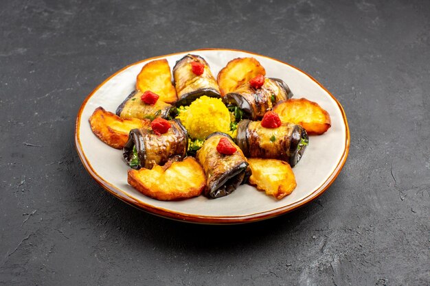 Vista frontal deliciosos rollos de berenjena plato cocido con papas al horno en el fondo oscuro plato de comida cocinar alimentos hornear papas fritas