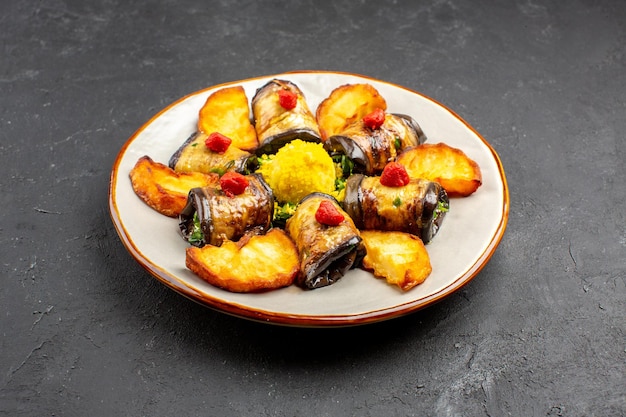 Vista frontal deliciosos rollos de berenjena plato cocido con papas al horno en el fondo oscuro plato de comida cocinar alimentos hornear papas fritas