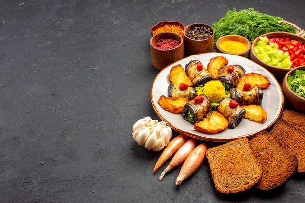 Vista frontal deliciosos rollos de berenjena plato cocido con patatas y hogazas de pan sobre fondo oscuro plato de comida para cocinar hornear patatas fritas