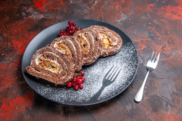 Vista frontal de deliciosos rollos de galletas con frutas sobre una superficie oscura