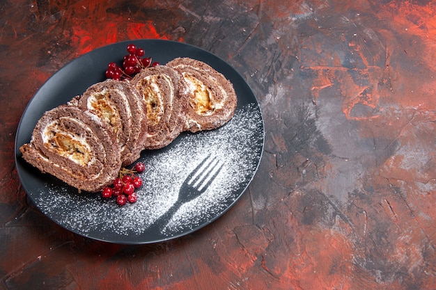 Vista frontal de deliciosos rollos de galletas con frutas sobre una superficie oscura