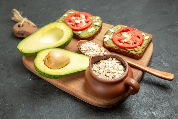 Vista frontal deliciosos sándwiches con aguacate y tomates rojos sobre fondo gris bocadillo pan sándwich de hamburguesa