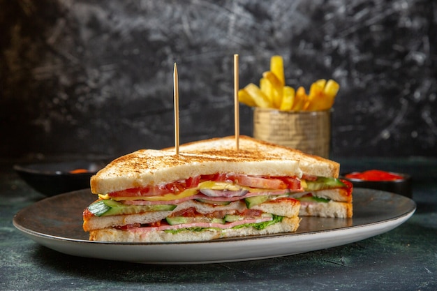 Vista frontal deliciosos sándwiches de jamón dentro de la placa con papas fritas superficie oscura