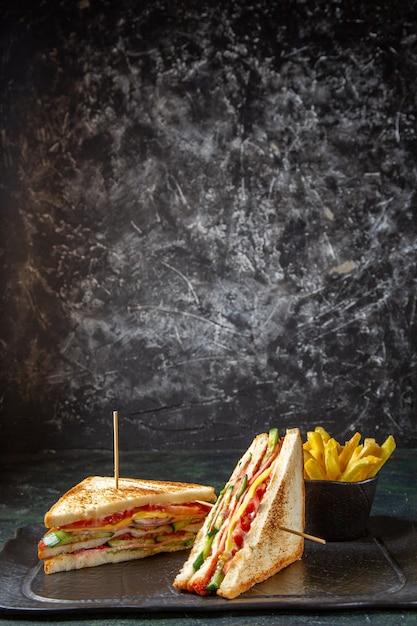 Foto gratuita vista frontal deliciosos sándwiches de jamón con papas fritas superficie oscura