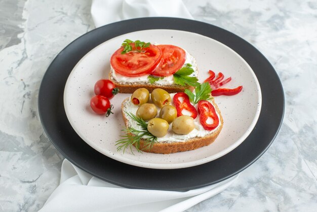 Vista frontal deliciosos sándwiches con tomates y aceitunas dentro del plato fondo blanco pan tostado almuerzo sándwich comida horizontal hamburguesa comida