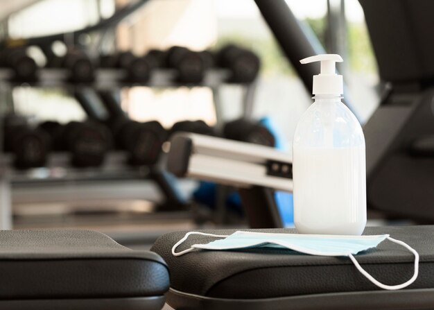 Vista frontal del desinfectante de manos y mascarilla médica en el gimnasio