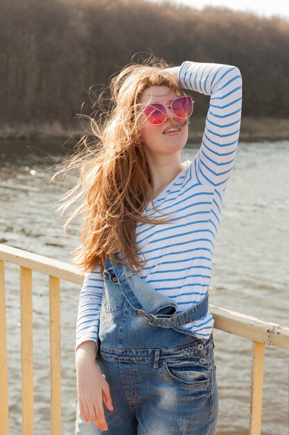 Vista frontal de la despreocupada mujer con gafas de sol junto al lago