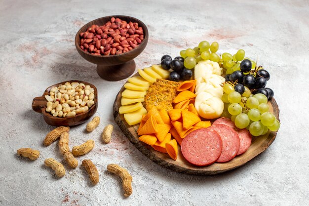 Vista frontal diferentes bocadillos cips salchichas queso y uvas frescas con nueces en espacio en blanco