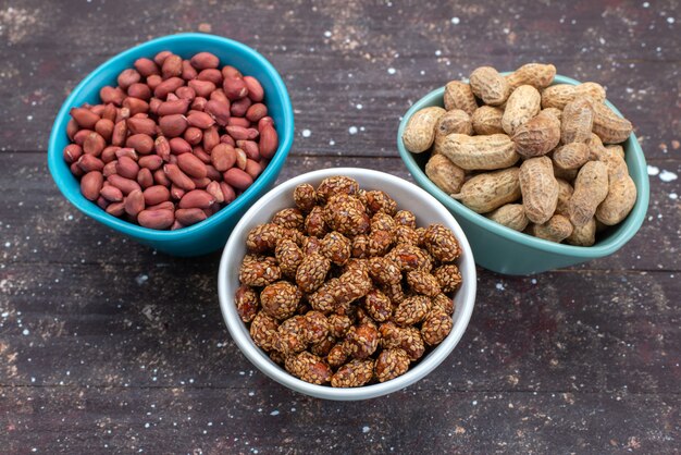 Vista frontal de diferentes composiciones de nueces dentro de las placas en la superficie gris