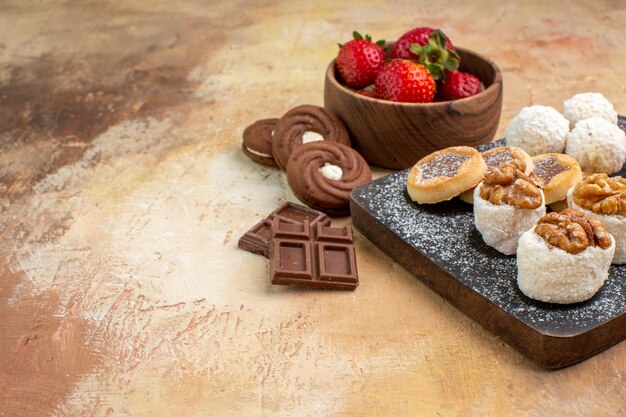 Vista frontal de diferentes dulces con galletas y frutas en la mesa de luz pastel de pastel de azúcar de frutas