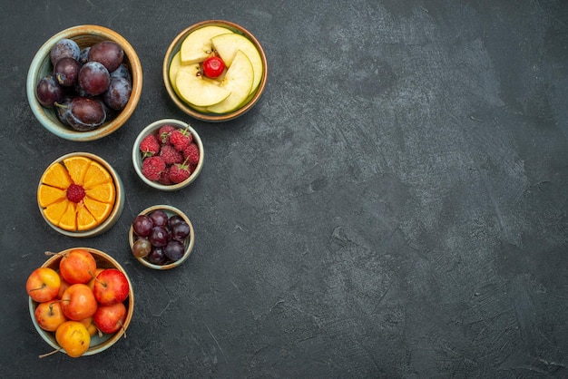 Vista frontal de diferentes frutas composición frutas frescas sobre fondo oscuro salud fruta fresca madura suave