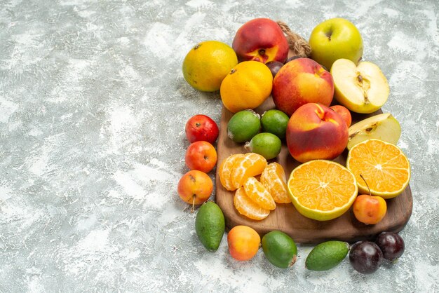 Vista frontal de diferentes frutas composición en rodajas y frutas frescas enteras en el espacio en blanco