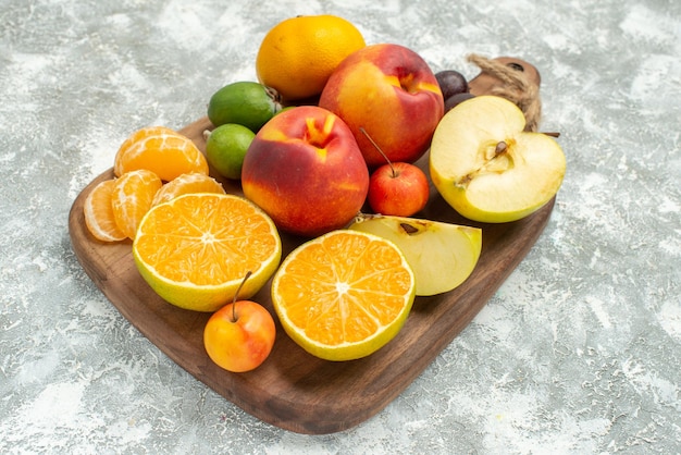 Vista frontal de diferentes frutas composición en rodajas y frutas frescas enteras en el espacio en blanco