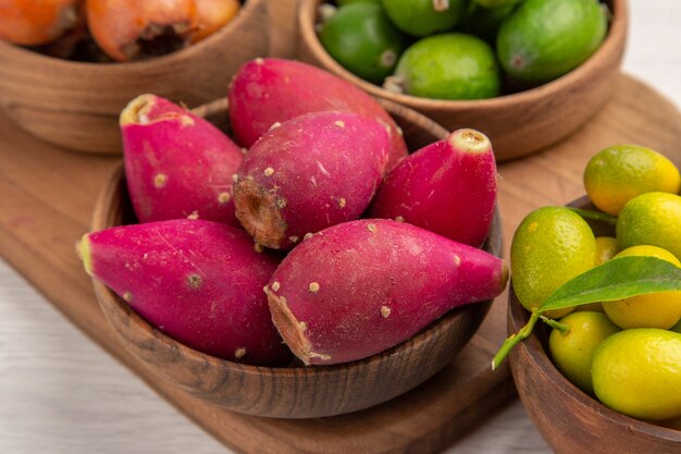 Foto gratuita vista frontal de diferentes frutas feijoas bayas y otras frutas dentro de placas sobre fondo blanco comida madura exótica foto color tropical