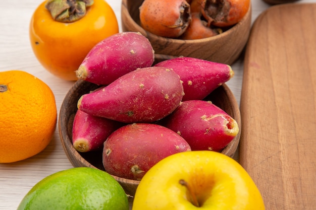 Vista frontal de diferentes frutas frescas dentro de las placas sobre fondo blanco color maduro tropical dieta exótica vida sana suave