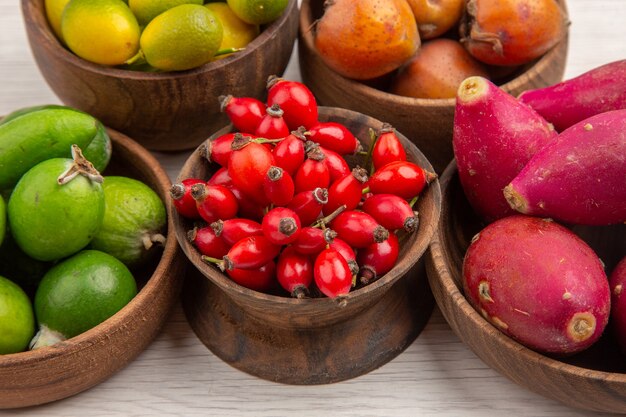 Vista frontal de diferentes frutas frescas dentro de las placas sobre fondo blanco color tropical vida sana árbol de bayas exóticas maduras