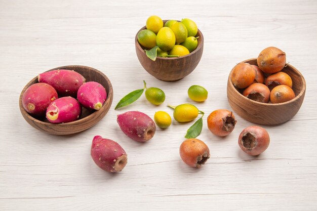 Vista frontal diferentes frutas frescas dentro de placas sobre fondo blanco frutas tropicales dieta madura color exótico