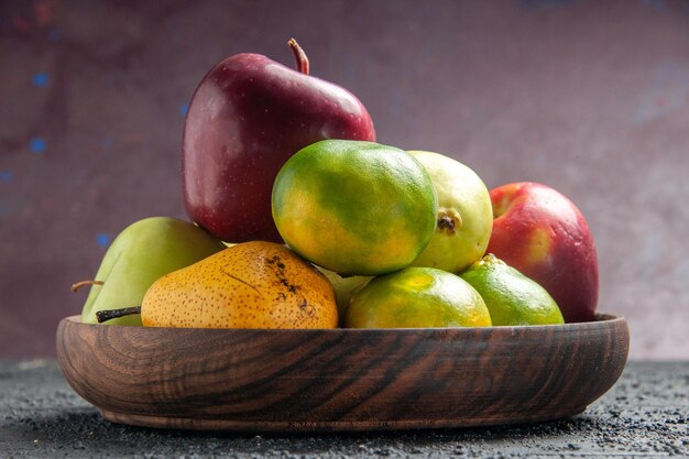 Vista frontal de diferentes frutas frescas manzanas, peras y mandarinas dentro de la placa en el escritorio azul oscuro composición de color de fruta madura fresca