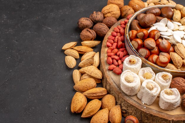 Vista frontal de diferentes frutos secos con confituras blancas sobre la superficie gris