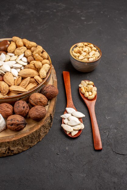 Vista frontal de diferentes frutos secos nueces frescas sobre superficie gris oscuro