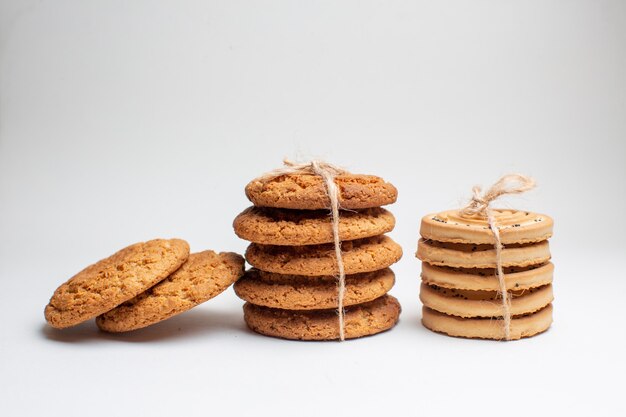 Vista frontal diferentes galletas dulces sobre fondo blanco.