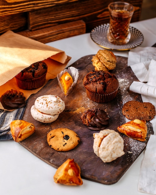 Foto gratuita vista frontal diferentes galletas y pasteles en la superficie marrón