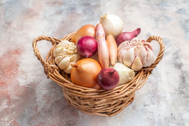 Vista frontal de diferentes ingredientes cebollas y ajo dentro de la canasta