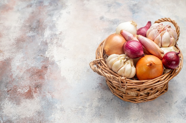 Foto gratuita vista frontal de diferentes ingredientes cebollas y ajo dentro de la canasta