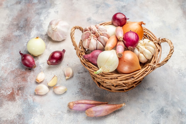 Vista frontal de diferentes ingredientes cebollas y ajo dentro de la canasta