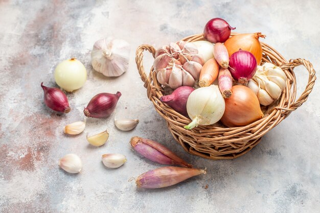 Vista frontal de diferentes ingredientes cebollas y ajo dentro de la canasta