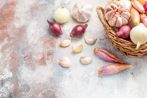 Vista frontal de diferentes ingredientes cebollas y ajo dentro de la canasta