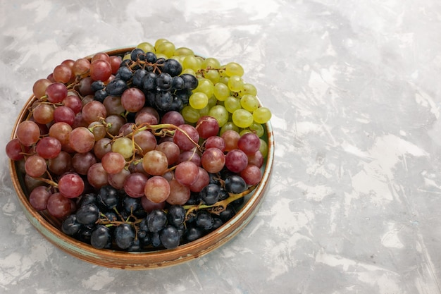 Vista frontal diferentes uvas jugosas frutas amargas suaves en la luz blanca escritorio fruta fresca jugo suave vino