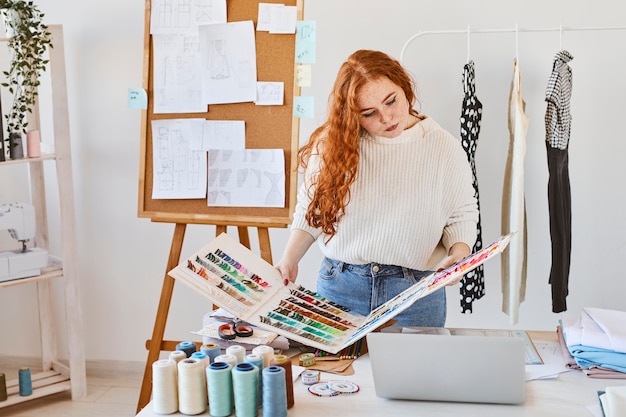 Vista frontal de la diseñadora de moda femenina en atelier con paleta de colores