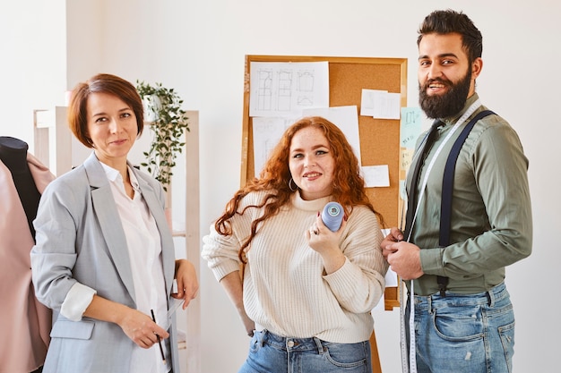 Vista frontal de los diseñadores de moda posando en su taller de negocios