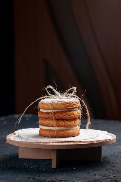 Vista frontal distante deliciosas galletas sándwich atado delicioso en el pastel de escritorio azul oscuro