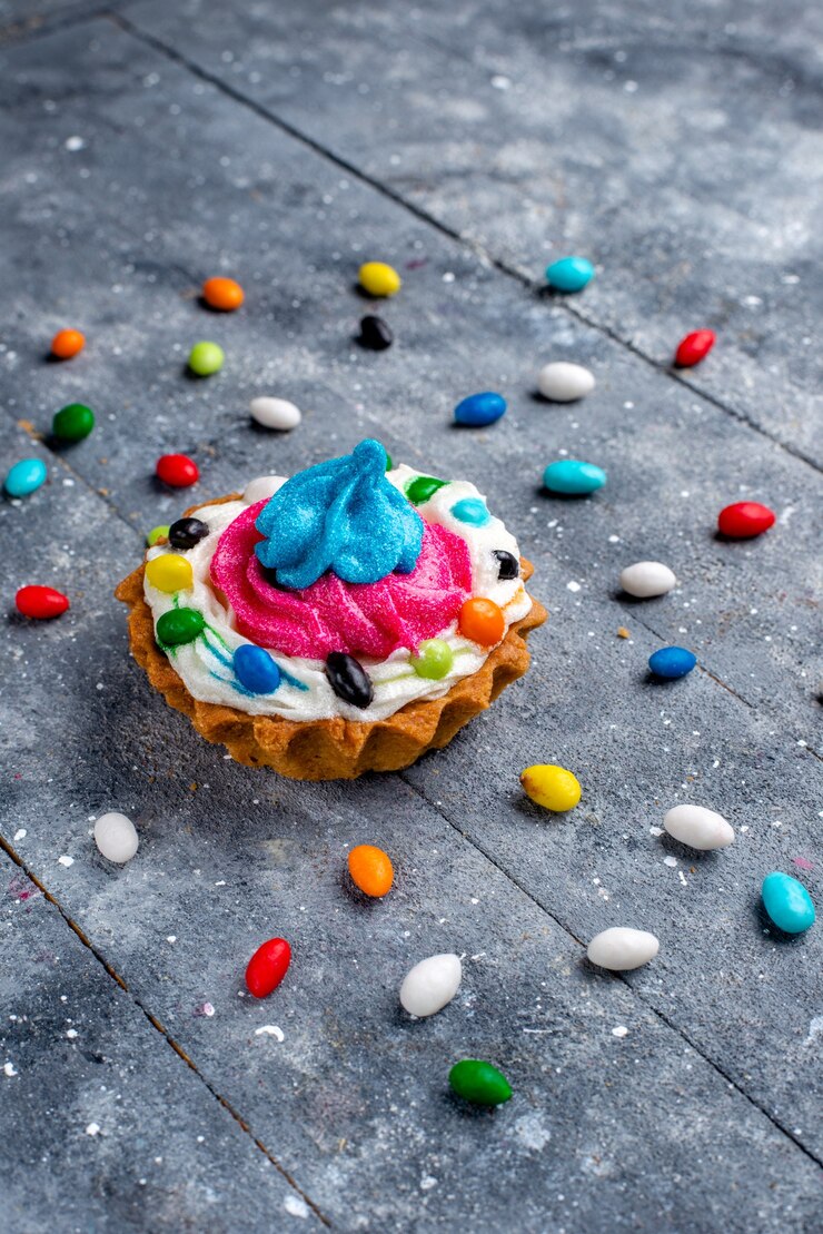 Foto gratuito vista frontal distante pequeño delicioso pastel con crema y diferentes caramelos de colores, todo en luz