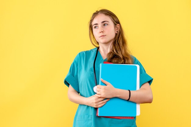 Vista frontal doctora con análisis sobre fondo amarillo claro médico hospital salud