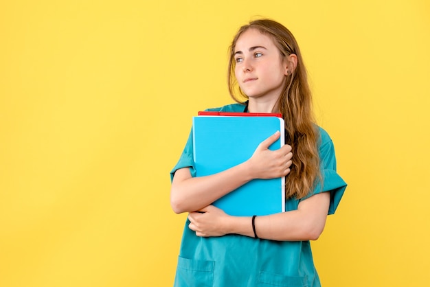 Vista frontal doctora con análisis sobre fondo amarillo enfermera médico hospital salud