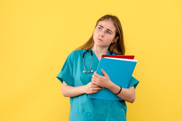 Vista frontal doctora con análisis sobre fondo amarillo salud enfermera hospital virus