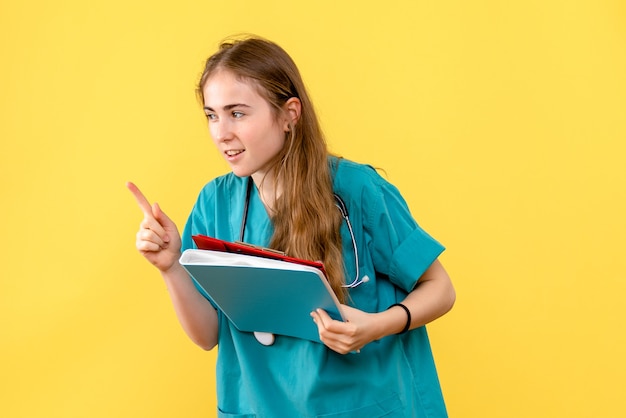 Vista frontal de la doctora con análisis sobre fondo amarillo virus de salud del hospital médico