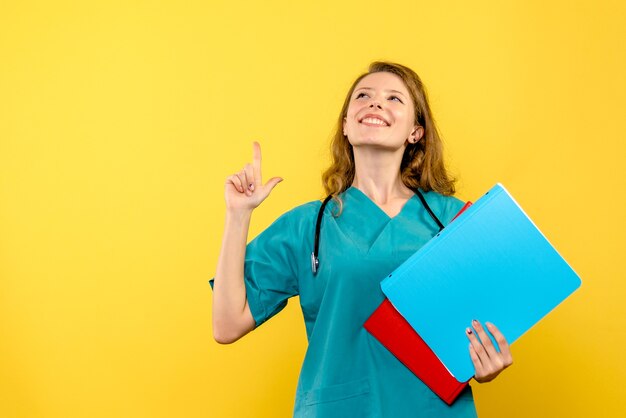 Vista frontal de la doctora con análisis sobre pared amarilla