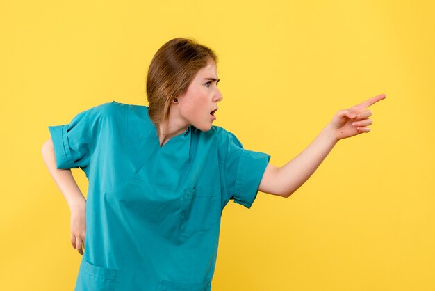 Vista frontal doctora apuntando sobre fondo amarillo emoción salud hospital médico