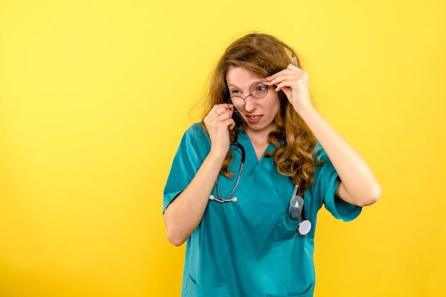 Vista frontal de la doctora arreglando sus gafas de sol en el espacio amarillo