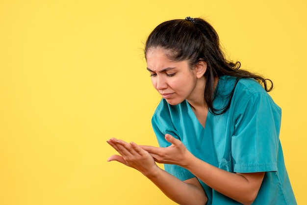 Foto gratuita vista frontal de la doctora bonita mirando sus manos en la pared amarilla