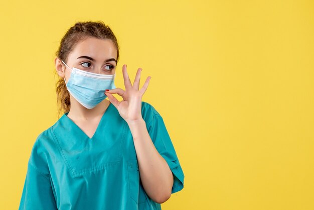 Vista frontal doctora en camisa y máscara médica, uniforme de color pandémico del virus covid-19 de la salud